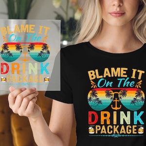 May include: A black t-shirt with a colorful graphic design. The graphic features a pair of sunglasses with palm trees and the text "Blame it on the drink package".
