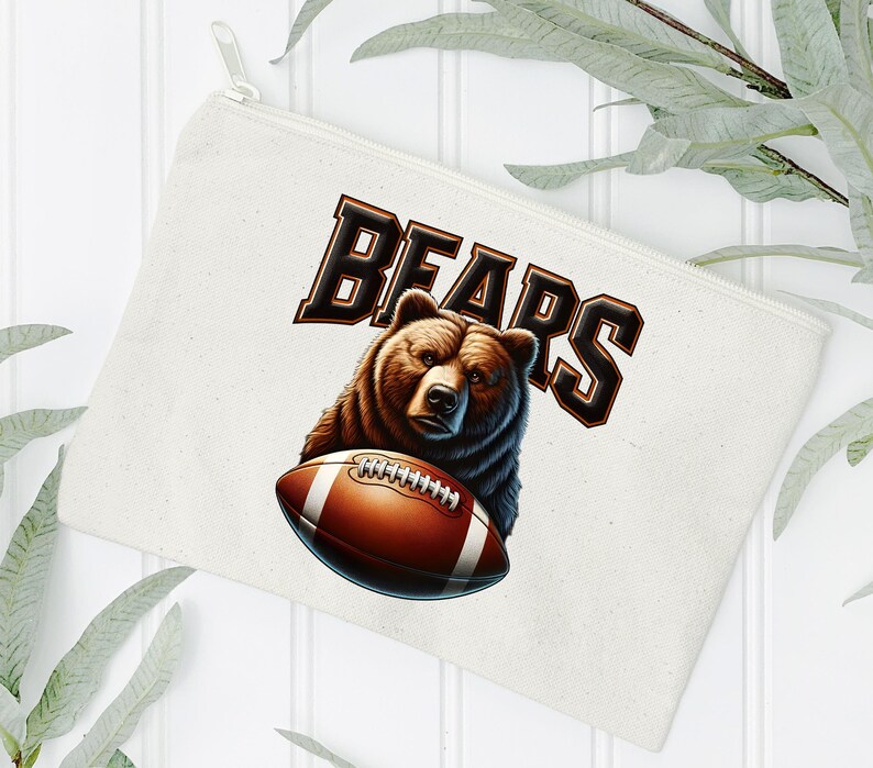 May include: A white canvas makeup bag with a brown bear holding a football. The text "BEARS" is printed in black letters.
