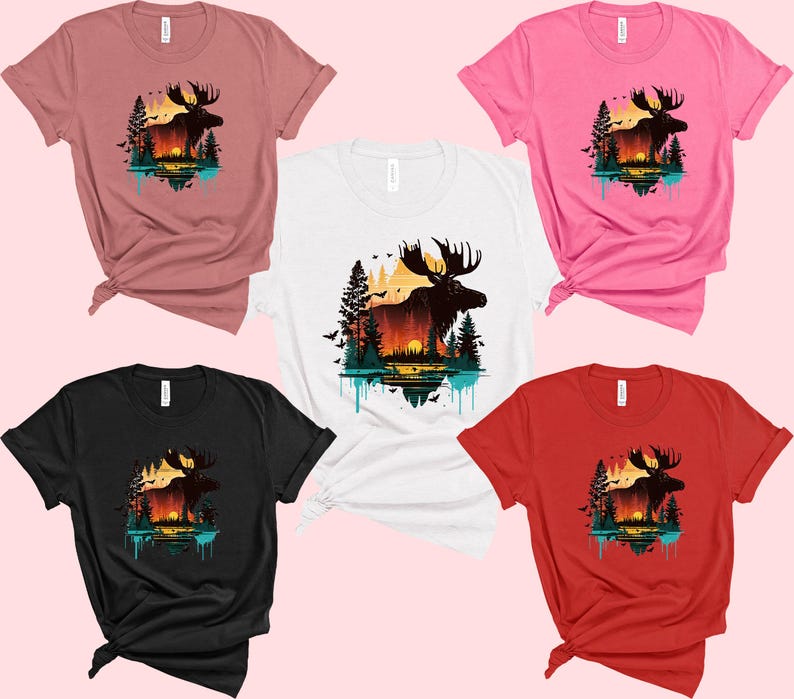 May include: Five different color t-shirts featuring a moose silhouette with a sunset and trees in the background. The t-shirts are available in pink, red, black, white, and dusty rose.