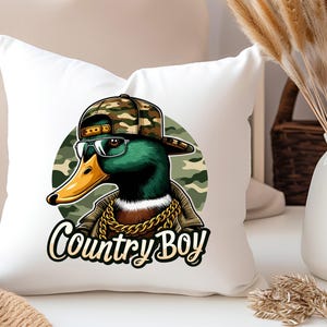 May include: A white cushion featuring a green duck wearing a camouflage hat and sunglasses. The duck is sporting a gold chain and the text "Country Boy" is printed beneath the duck.