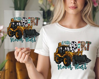 May include: A white t-shirt with a yellow excavator graphic and the text "A little dirt never hurt". The excavator is decorated with a colorful pattern of animal print, stripes, and floral designs.