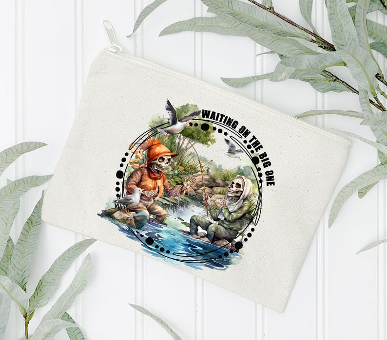 K&ouml;nnte beinhalten: Eine wei&szlig;e Canvas-Kosmetiktasche mit einer Schwarzwei&szlig;illustration von zwei Skeletten beim Angeln. Der Text "Waiting on the Big One" ist auf der Tasche aufgedruckt.