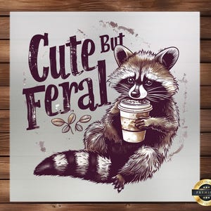 May include: A cute raccoon with a cup of coffee, with the text "Cute But Feral" in purple lettering.