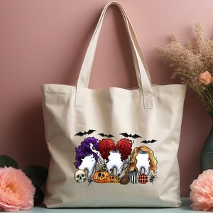 May include: A white canvas tote bag with a Halloween-themed design featuring three cartoon teeth with hair, bats, pumpkins, and a skull. The text "Boo!" is printed on the bag.