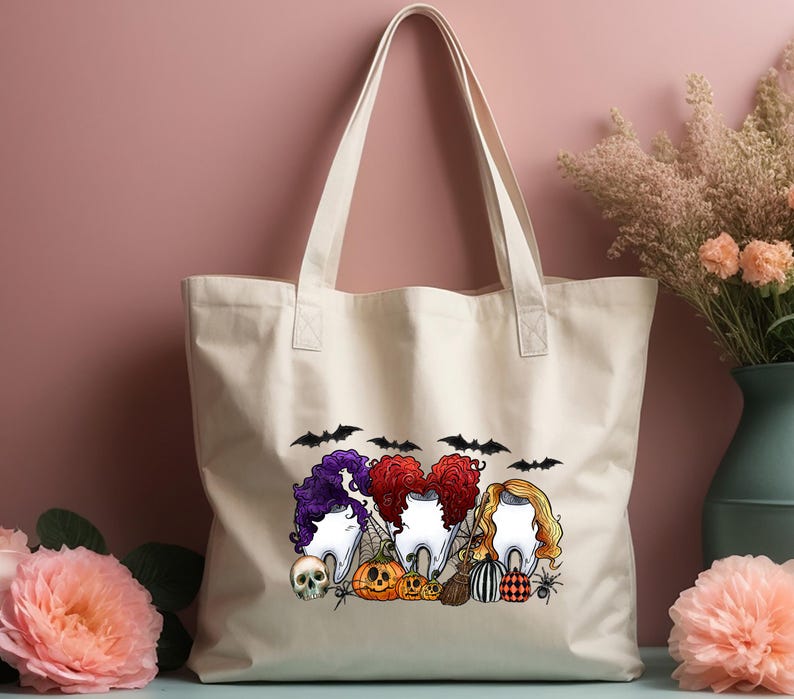 May include: A white canvas tote bag with a Halloween-themed design featuring three cartoon teeth with hair, bats, pumpkins, and a skull. The text "Boo!" is printed on the bag.