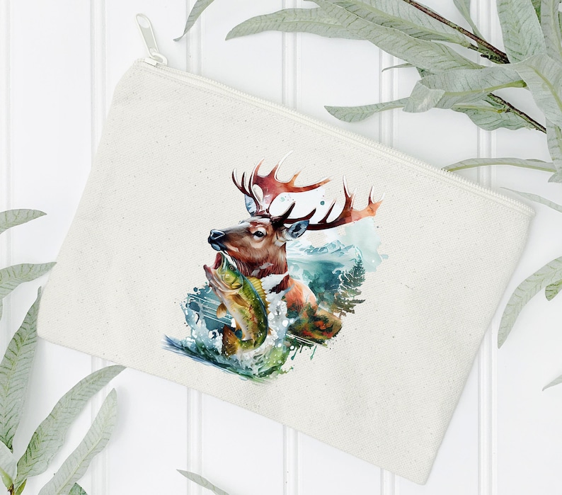 May include: A cream-coloured zipped pouch featuring a watercolour illustration of a deer with large antlers, holding a fish in its mouth. The artwork includes elements of water and a mountain landscape.