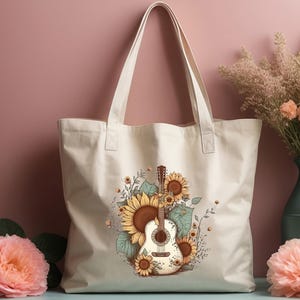 May include: A white canvas tote bag with a design of a guitar surrounded by sunflowers. The bag has brown straps.