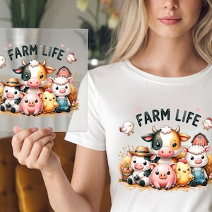 May include: A clear square with the words "FARM LIFE" and a cartoon illustration of farm animals, including a cow, pig, sheep, and chicken. The image is on a white t-shirt.