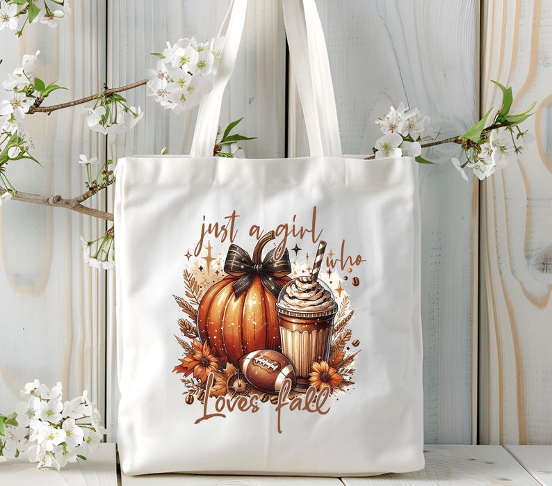 May include: White tote bag with a brown pumpkin, a cup of coffee, and a football. The text on the bag reads "Just a girl who loves fall".