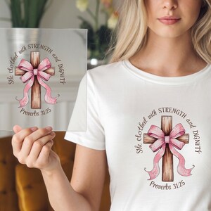 May include: A white t-shirt with a pink and brown cross and the text "She is clothed with strength and dignity. Proverbs 31:25"