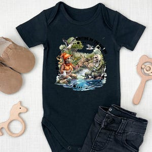 K&ouml;nnte beinhalten: Schwarzer Baby-Strampler mit einem Motiv von zwei Skeletten beim Angeln. Der Text "Waiting on the tide to come in" ist auf dem Strampler aufgedruckt.