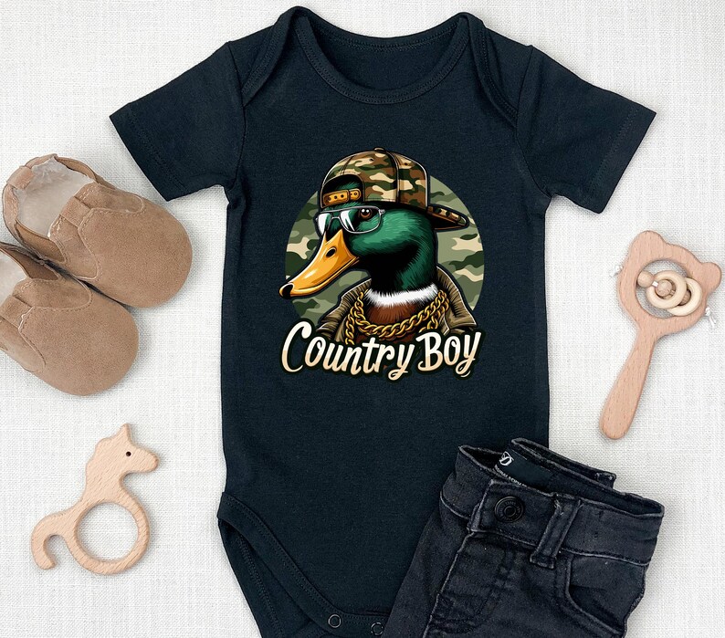 May include: Black baby bodysuit featuring a cartoon illustration of a duck wearing a camouflage hat, sunglasses, and a gold chain. The text "Country Boy" is printed below the duck.
