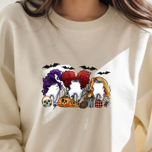 May include: A white sweatshirt with a Halloween-themed graphic featuring three cartoon teeth dressed as witches with pumpkins and bats. The text "Boo-tiful" is printed on the sweatshirt.