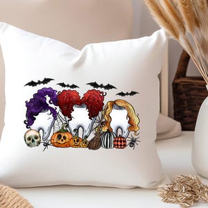 May include: White throw pillow with a Halloween-themed design featuring four cartoon teeth with witch hats and hair, bats, pumpkins, and a spider. The text "Boo" is written in black.