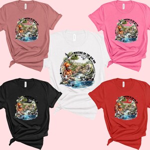 K&ouml;nnte beinhalten: F&uuml;nf T-Shirts in verschiedenen Farben, jedes mit einem Motiv von zwei Skeletten beim Angeln mit dem Text "Waiting on the big one". Die T-Shirts sind in Pink, Rot, Schwarz, Wei&szlig; und Braun erh&auml;ltlich.