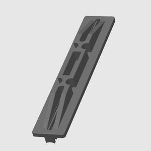 Op de afbeelding: Een grijs rechthoekig object met een reeks uitgesneden vormen. Het object heeft een lang, smal ontwerp met een symmetrisch patroon van rechthoekige en gebogen openingen. De algehele uitstraling is een eenvoudig, geometrisch ontwerp.