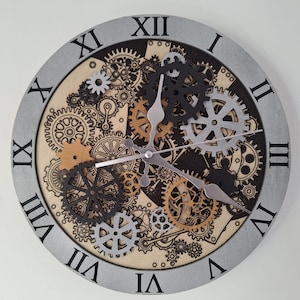 Peut inclure: Une horloge murale ronde de style steampunk, avec une bordure grise et des chiffres romains. Le cadran présente un arrangement complexe d'engrenages noirs, argentés et dorés. Les aiguilles sont argentées.