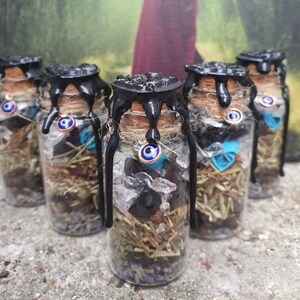 Peut inclure: Six petites bouteilles en verre avec des sceaux de cire noire et des charmes bleus de mauvais œil. Les bouteilles sont remplies d'herbes séchées, de cristaux et d'autres ingrédients magiques.