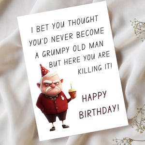 May include: A white greeting card with the text "I BET YOU THOUGHT YOU'D NEVER BECOME A GRUMPY OLD MAN BUT HERE YOU ARE KILLING IT! HAPPY BIRTHDAY!" features a cartoon of an old man holding a cupcake.