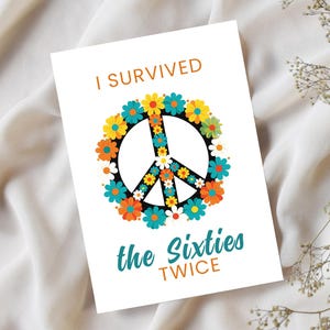 May include: A white card with the text "I Survived the Sixties TWICE" in orange and teal. The peace sign is filled with colorful flowers in a circular pattern. The card is on a white fabric background.