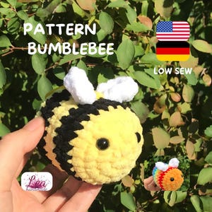 Könnte beinhalten: Gehäkelte Biene mit gelben und schwarzen Streifen, weißen Flügeln und schwarzen Augen. Der Text "PATTERN BUMBLEBEE" und "LOW SEW" sind im Bild zu sehen. Die amerikanische und deutsche Flagge sind ebenfalls abgebildet.
