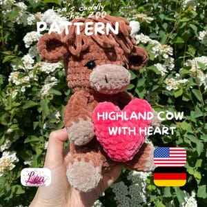 May include: A handmade brown crochet Highland cow plushie holding a pink heart. The heart reads "Highland Cow With Heart." The plushie has a light brown muzzle and hooves. The text "Lea's cuddly crochet zoo PATTERN" is at the top.