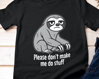 Pode incluir: Camiseta preta com uma ilustração de bicho-preguiça cinza e o texto "Please don't make me do stuff". A preguiça tem uma expressão mal-humorada. A camisa é combinada com jeans azuis, uma camisa xadrez e um chapéu.