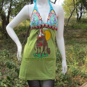 May include: Green halter top with a colorful floral print and a graphic of a camel with a rider. The text "Kingdom of Bahrain" is printed on the front of the shirt.