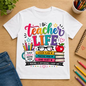 May include: White t-shirt with a colorful graphic that reads "Teacher Life." The design includes pencils, books, an apple, and the phrases "Teach Love Inspire Grow," "Lesson Plans," "Positive Mind," and "Kind Heart." The shirt is a crew neck.