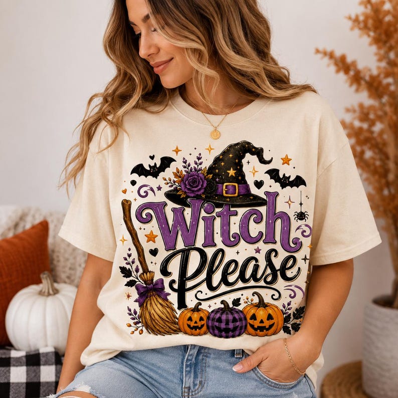 May include: A cream-colored t-shirt featuring a graphic print with the text "Witch Please" in purple and black. The design includes a black witch hat with a purple band, a broomstick, three pumpkins, bats, stars, and a purple flower.