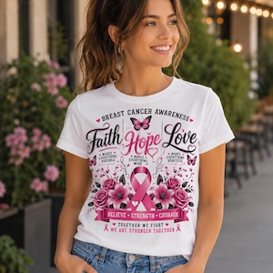 May include: White t-shirt with a pink ribbon and floral design, promoting breast cancer awareness. The shirt features the words "Faith, Hope, Love" and other supportive phrases. Butterflies and hearts accent the design.