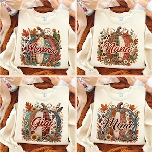 Könnte beinhalten: Vier cremefarbene Sweatshirts mit Rundhalsausschnitt und einem zentralen Kürbis-Motiv, das mit verschiedenen Mustern, Herbstblättern und Western-Akzenten verziert ist. Jedes Sweatshirt zeigt einen anderen Namen in Schreibschrift: Mama, Nana, Gigi und Mimi.