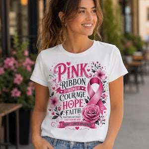 May include: White t-shirt with a pink ribbon design, floral accents, and the words "Pink Ribbon Strength Courage Hope Faith" and "Breast Cancer Awareness". The design includes a pink ribbon and a pink rose.