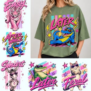 Puede incluir: Camiseta verde oliva con un gráfico de un caimán azul con gafas de sol y la palabra "LATER" en rosa y amarillo. Otros gráficos incluyen un tigre rosa, un caimán azul, un burro, un caimán verde y un gato.