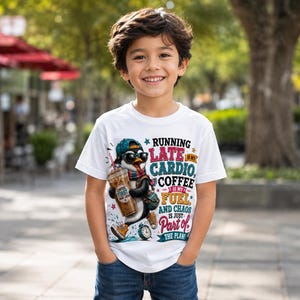 K&ouml;nnte beinhalten: Ein wei&szlig;es kurz&auml;rmeliges T-Shirt mit einer Grafik eines Pinguins, der eine Sonnenbrille, eine M&uuml;tze und einen Schal tr&auml;gt und einen Eiskaffee h&auml;lt. Der Text lautet: RUNNING LATE IS MY CARDIO, COFFEE IS MY FUEL, AND CHAOS IS JUST PART OF THE PLAN.