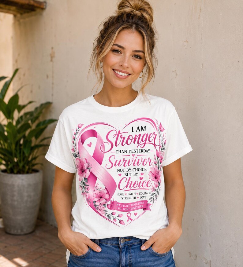 May include: White t-shirt with a pink ribbon and floral heart design. The text reads "I AM Stronger Than Yesterday Survivor Not By Choice But By Choice". The shirt also includes the words "Hope, Faith, Courage, Strength, Love" and "We Fight Together, We Win Together".