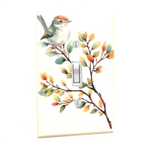 May include: A decorative light switch cover featuring a watercolor painting of a small bird perched on a branch with colorful leaves. The bird has a red-brown head and a light green body. The switch and screws are silver.