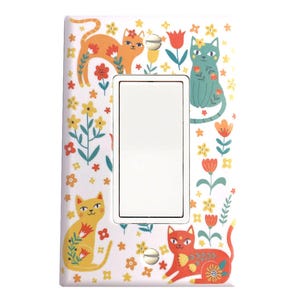 May include: A white light switch cover with a colorful design featuring cats and flowers. The cats are orange, yellow, and green, and the flowers are red, yellow, and orange.