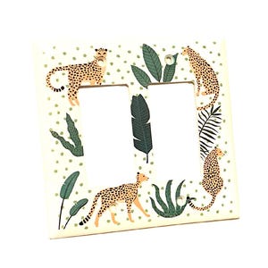 May include: A decorative double light switch cover featuring a cream background with a repeating pattern of small green dots. The cover is adorned with illustrations of cheetahs and tropical foliage in shades of green and brown.
