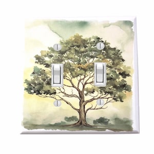 May include: A double light switch cover with a watercolor painting of a green tree with a yellow and green background.