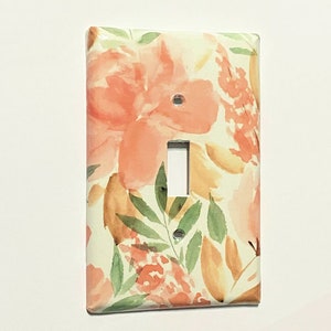 May include: A light switch cover with a floral design featuring peach, yellow, and green watercolor flowers on a white background.