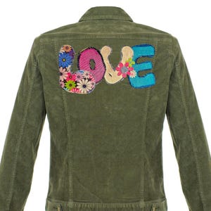 May include: Olive green corduroy jacket with the word "LOVE" appliqued on the back. The letters are in various colors and floral patterns. The jacket has a button-down front and long sleeves.
