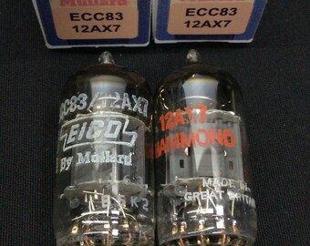 May include: Two Mullard ECC83 12AX7 vacuum tubes with their original blue and white boxes. The tubes feature clear glass envelopes with internal metal components and printed text including EICO, Hammond, and Made in Great Britain.