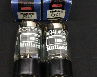 May include: Two Mullard GZ34/5AR4 electron tubes with black bases and metal pins, each paired with its original blue and black cardboard box labeled A Quality Product Electron Tube and featuring the IEC and Mullard brand logos.