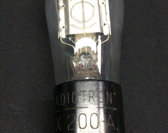 Może przedstawiać: Przezroczysta szklana lampa próżniowa z czarną podstawą z białym napisem RADIOTRON UX 200 A. Wewnętrzne metalowe elementy są widoczne przez szklaną obudowę, a dwa metalowe piny wystają z dolnej części czarnej cylindrycznej podstawy.