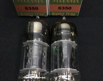 May include: Two Sylvania 6350 radio tubes in their original green and white cardboard boxes. Each box features the Sylvania brand name, the number 6350, and a triangular logo with an S and a lightning bolt. The glass tubes have metal pins.