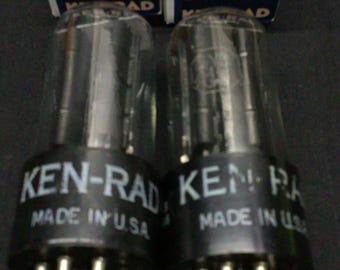 May include: Two Ken-Rad 5Y3GT radio tubes with clear glass envelopes and black bases, each labeled Made in U.S.A. The tubes are positioned in front of their original red, white, and blue cardboard boxes, which feature the Ken-Rad brand name.