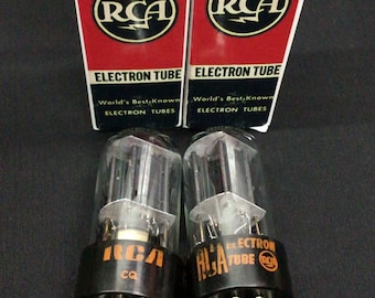 May include: Two RCA 6SN7GTB Radiotron electron tubes with their original red, white, and black cardboard boxes. Each glass vacuum tube features a black base with metal pins and the RCA logo printed in orange on the side of the base.