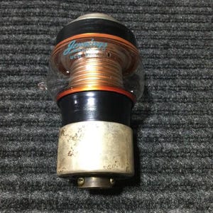 May include: A vintage Jennings vacuum capacitor with copper coils, black and orange accents, and a silver base. The name "Jennings" is visible in a teal script. The capacitor is encased in a clear plastic housing.