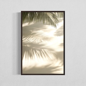 Könnte beinhalten: Gerahmter Kunstdruck mit einem sepiafarbenen Bild von Palmenwedeln und ihren Schatten. Die Schatten erzeugen ein strukturiertes Muster auf dem hellen Hintergrund. Der dunkelbraune Rahmen bildet einen kontrastierenden Rand zur tropischen Szene.